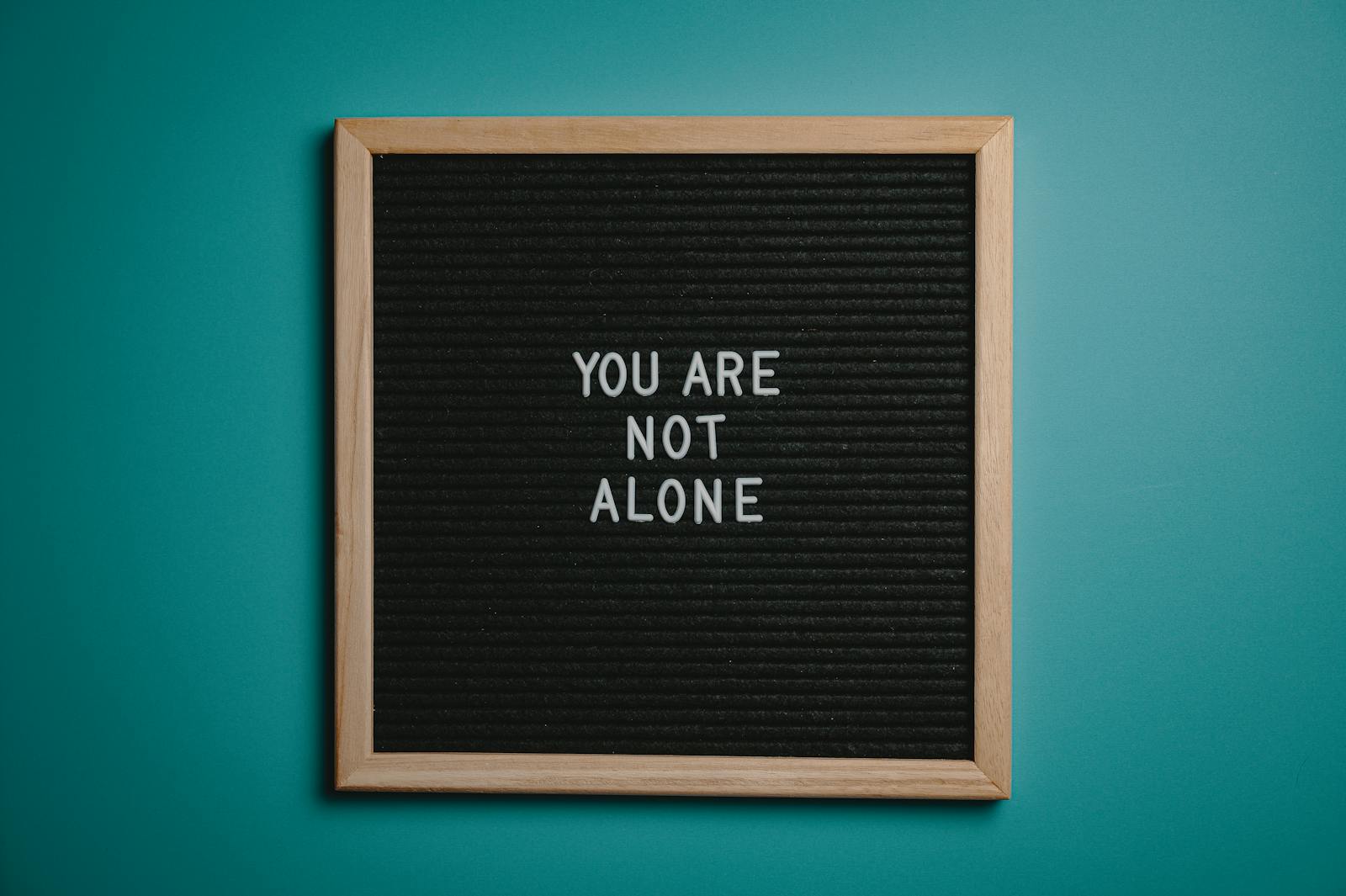 A wooden letter board displays a motivational message against a teal background. mental health recovery