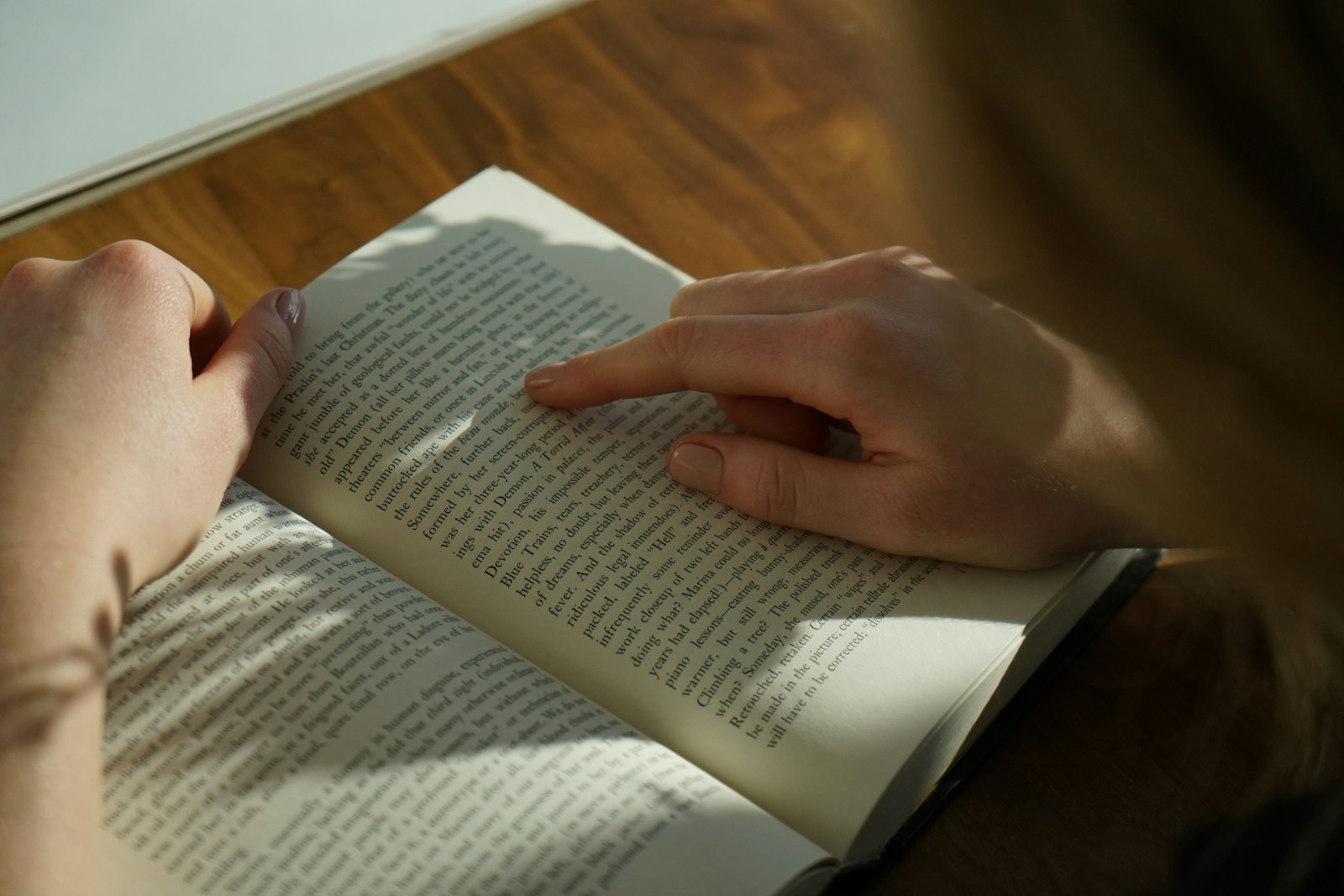 person reading book on brown wooden table taken at daytome self love books
