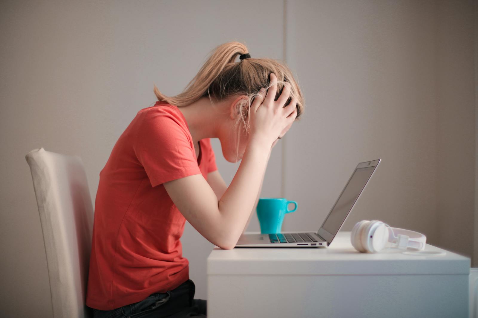 Young woman feeling stressed while studying at home with a laptop and coffee cup. distinct anxiety