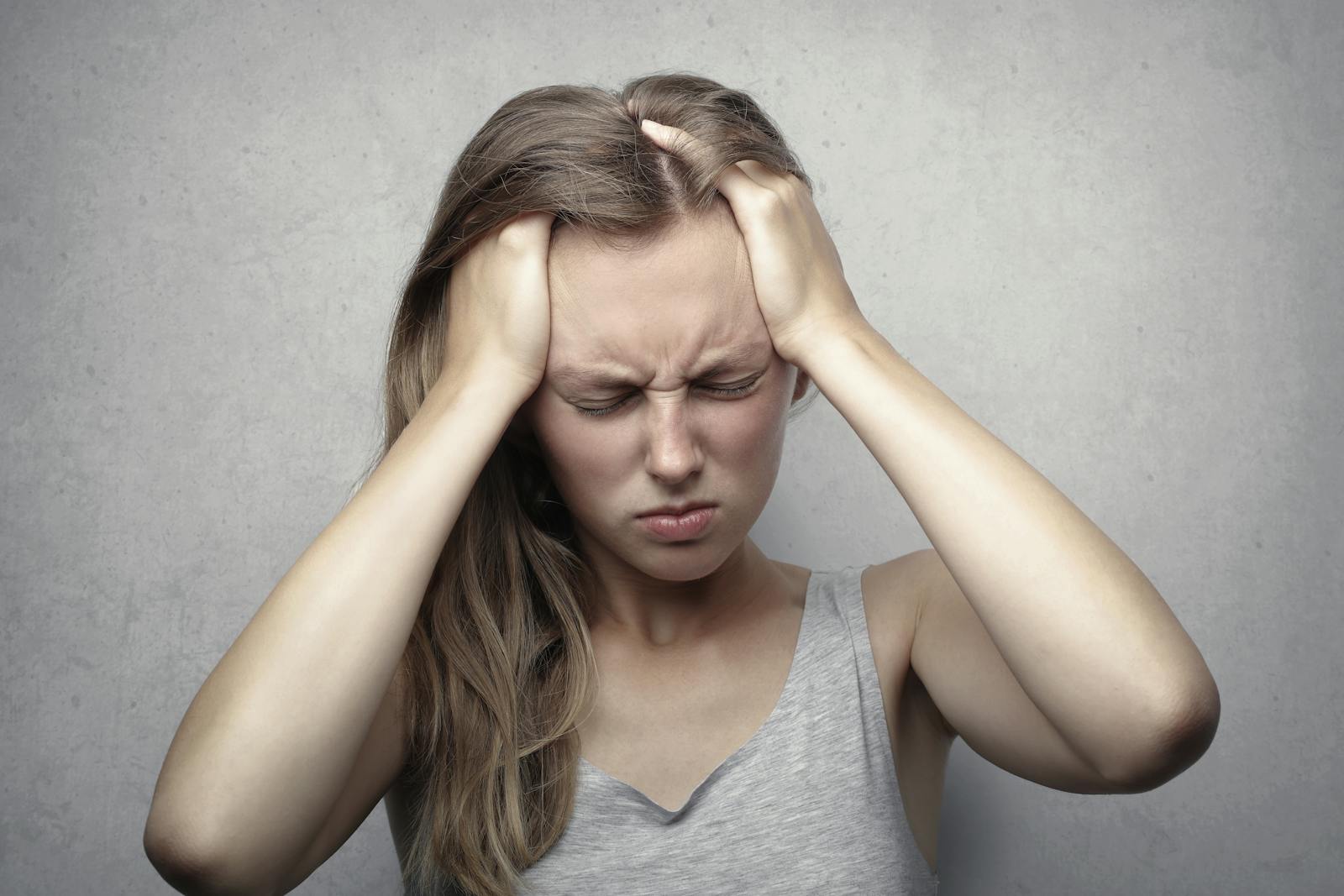 Young woman expressing stress and frustration while holding her head. depression counseling