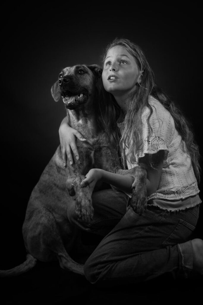 Black and white portrait of a girl hugging a dog, conveying deep emotion and connection.