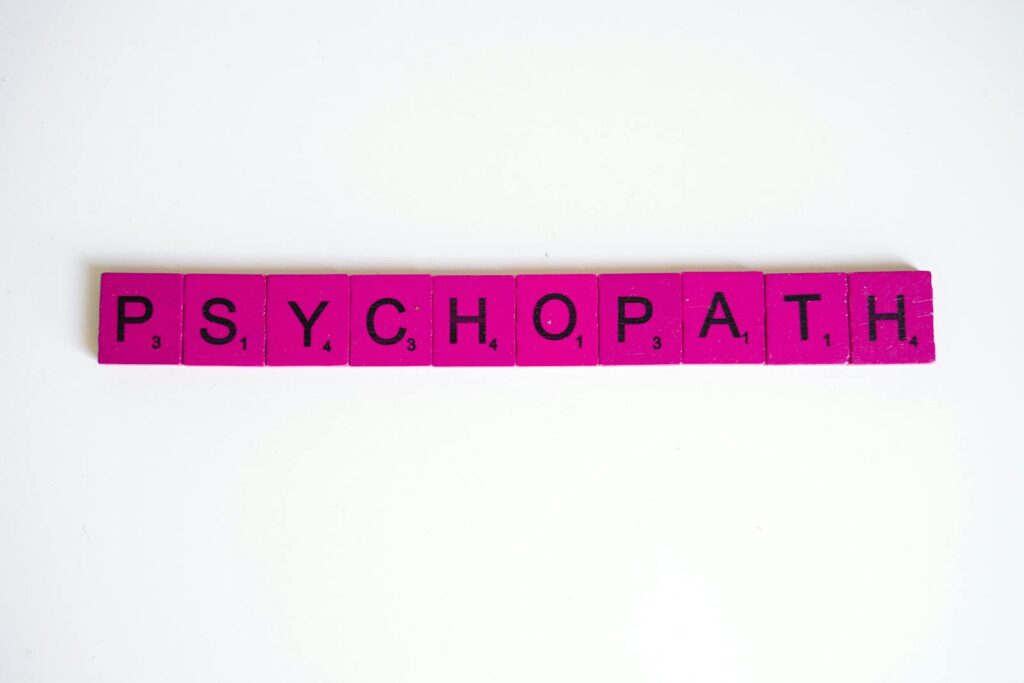 Pink Scrabble tiles spelling 'Psychopath' on a white background, artistic representation.
