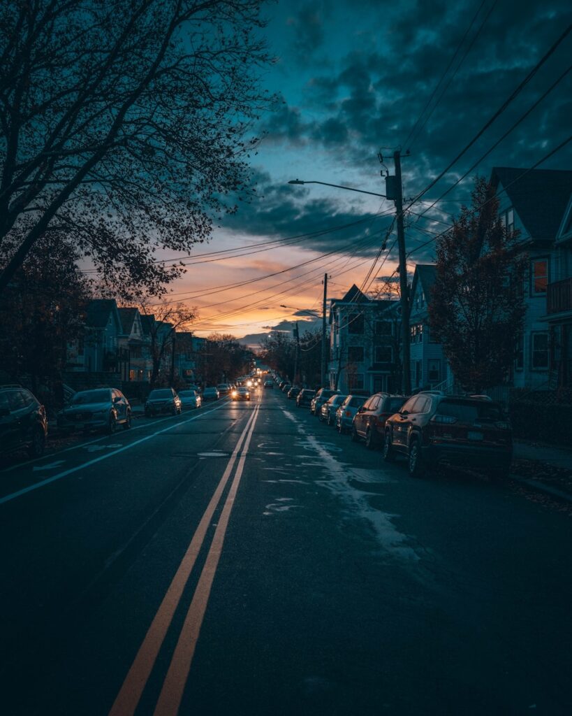 a city street at night with cars parked on the side of the road