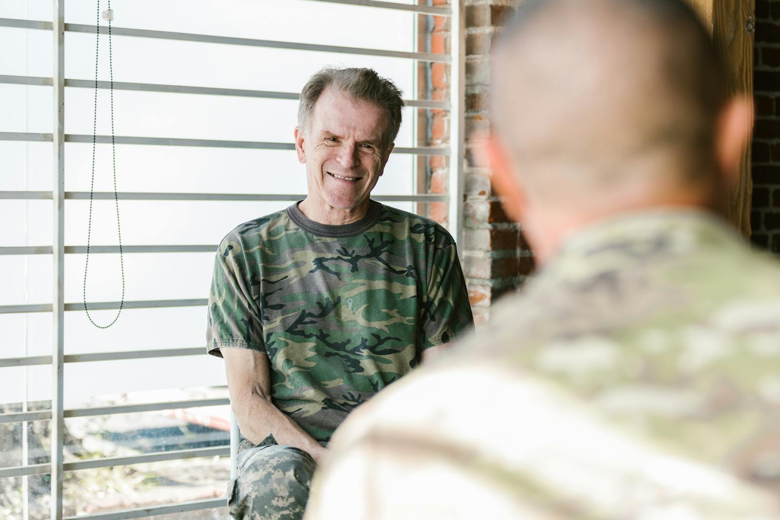 Senior and fellow military veterans engaging in a supportive therapy session indoors. C-PTSD