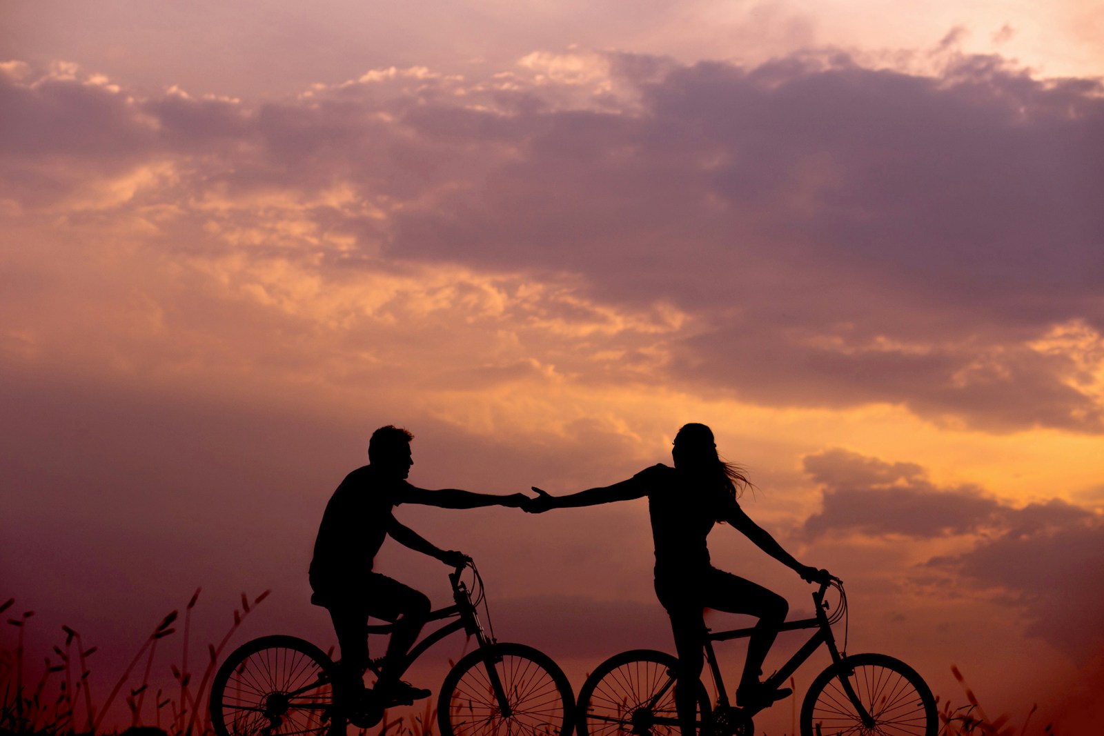 woman on bike reaching for man's hand behind her also on bike Relationship Issues