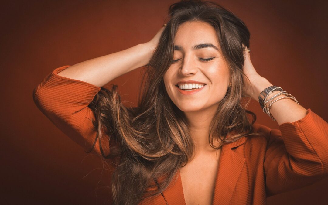 smiling woman in brown top holding hairs Life Coaching