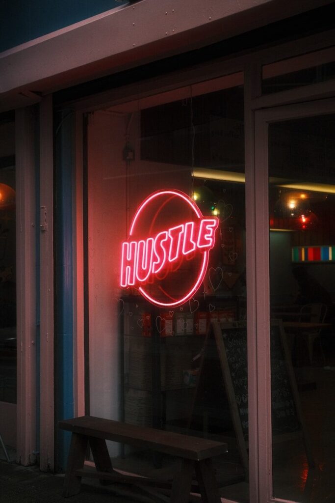 Red neon sign that says hustle in circle "hustle"