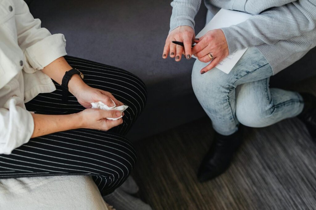 Close-up of a therapist and client during a counseling session, focusing on hands holding notes.