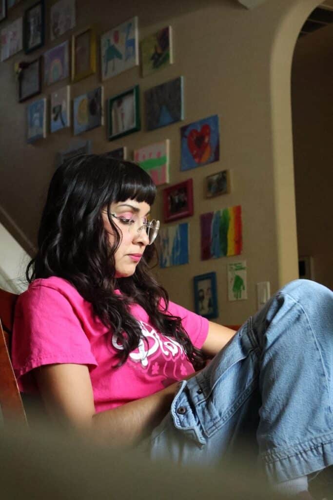 A woman sits, lost in thought, by artwork.