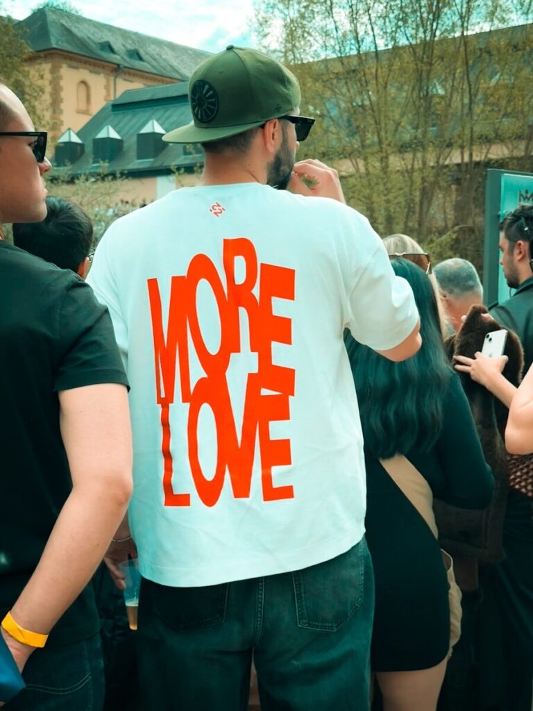 Man wearing white t-shirt with orange "more love" text.
