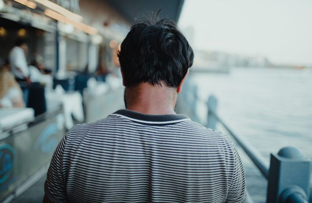 Back view of a man wearing a striped shirt walking by the Istanbul waterfront.