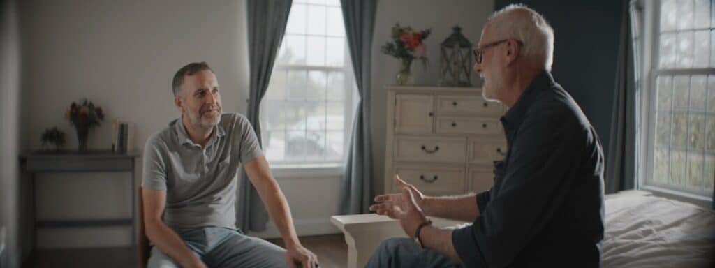 Two men talking in a sunlit room