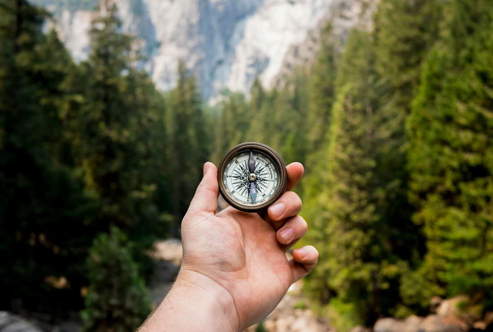 Photo by Jamie Street person holding compass facing towards green pine trees The Hidden Struggles: Anxiety Symptoms in Men and Their Impact on Well-Being