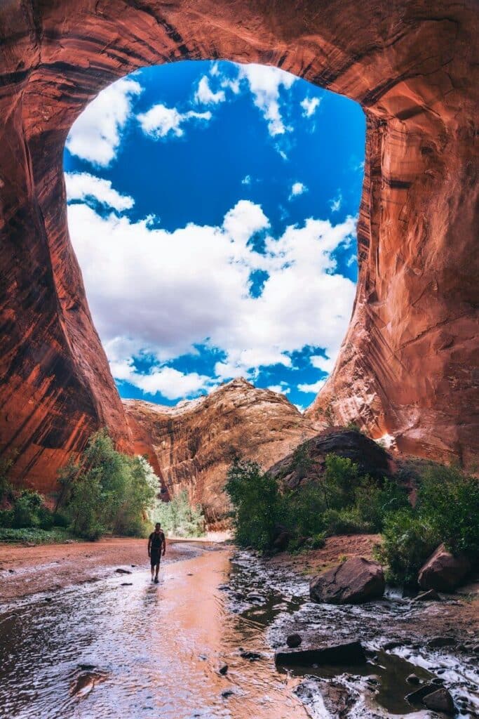 man walking under cave during daytime