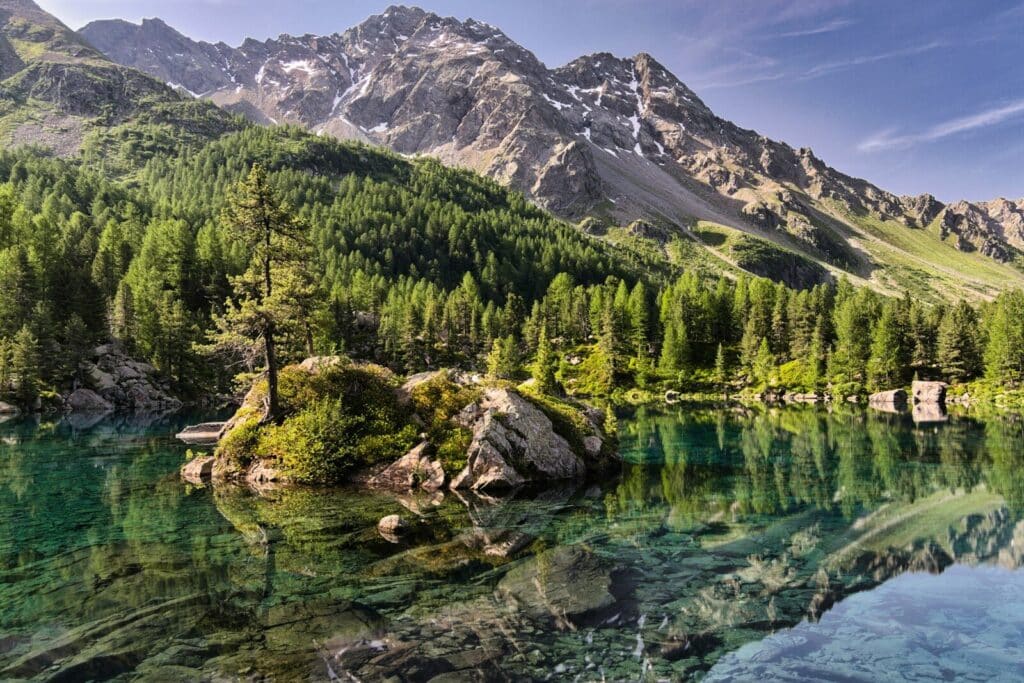 A crystal clear lake reflects a forest and mountains